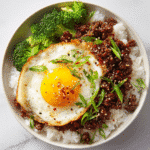 Korean ground beef bowl served over white rice with green onions, sesame seeds, fried egg, and steamed broccoli