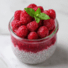 Raspberry chia pudding in glass jar with fresh raspberries and mint