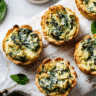 Mini Spinach Artichoke Cups freshly baked on a white board