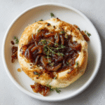 Warm Baked Brie with Caramelized Onions and Fig Spread on white plate
