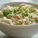 Homemade Potato Noodles (Korean Style) in white ceramic bowl with green onions