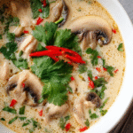 Thai Coconut Chicken Soup (Tom Kha Gai) in white bowl with fresh herbs