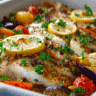 Mediterranean baked fish in ceramic baking dish with roasted vegetables