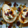 Baked Pears with Goat Cheese, Honey, and Cranberries on a white plate