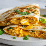 Spicy Cheesy Chicken Quesadilla Wraps on white plate with cilantro
