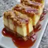 Caramel apple cheesecake bars drizzled with caramel and topped with apple slices