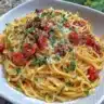 Creamy tomato garlic pasta served in a white bowl with parsley garnish