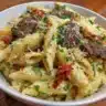 Creamy high protein beef pasta garnished with fresh herbs on a plate