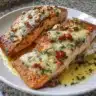 Plate of Garlic Butter Salmon with herbs and lemon garnish.