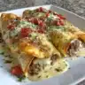 Delicious ground beef enchiladas topped with cheese and sauce, ready to serve.