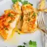 Plate of halibut fillet with lemon butter sauce garnished with herbs