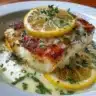 Plate of halibut with lemon butter sauce garnished with fresh herbs