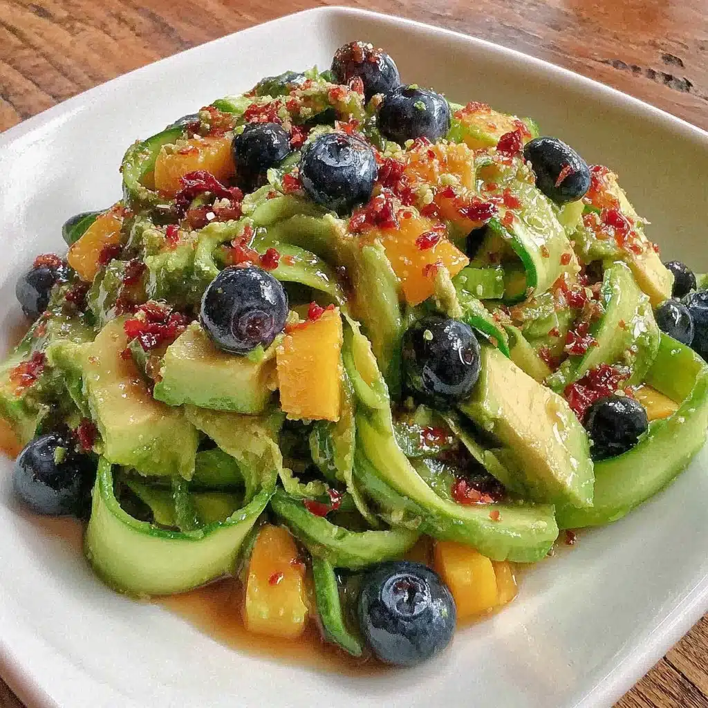 Mango cucumber salad topped with blueberries and avocado in a colorful bowl.