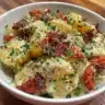 Mediterranean Potato Salad with olives, tomatoes, and herbs in a bowl.