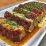 Delicious garlic parmesan meatloaf sliced on a plate with herbs garnish