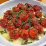 Bowl of roasted cherry tomatoes garnished with herbs