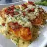 Smothered cheesy sour cream chicken dish served with garnishes.