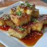 Crispy air fryer tofu drizzled with sticky sesame sauce on a plate