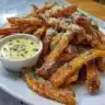 Crispy air fryer sweet potato fries served with dipping sauce on a plate.