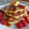 Deliciously fluffy pancakes stacked on a plate with syrup and berries