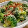 A plate of Garlic Parmesan Broccoli garnished with parmesan cheese and garlic.