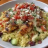 Healthy Greek Chicken Quinoa Bowl topped with fresh vegetables and herbs