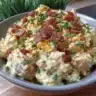 Creamy steakhouse potato salad served in a bowl with fresh herbs