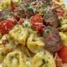 Cracked garlic steak tortellini in creamy sauce topped with herbs