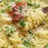 Plate of garlic parmesan pasta garnished with parsley and grated cheese.