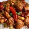 A plate of Kung Pao Chicken garnished with peanuts and vegetables