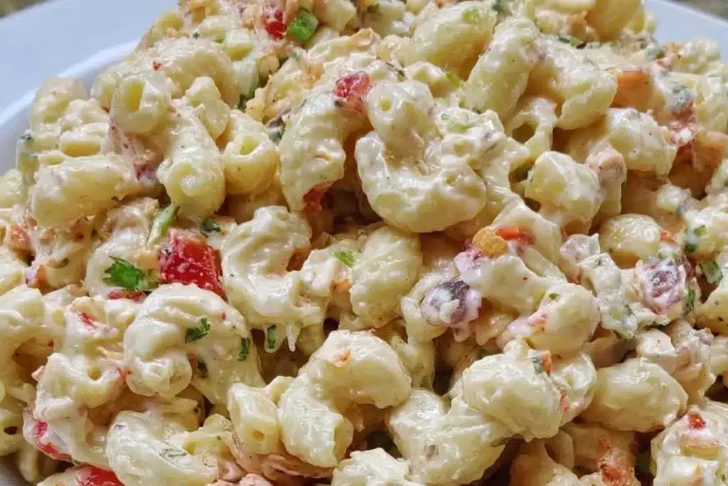 Delicious creamy macaroni salad served in a bowl, garnished with herbs.