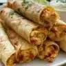 Oven baked chicken taquitos on a plate topped with salsa and avocado