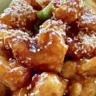 Plate of sesame chicken garnished with sesame seeds and vegetables