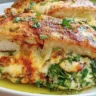 Juicy spinach stuffed chicken breasts served on a plate with creamy sauce.