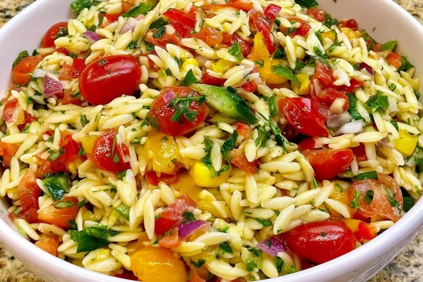 Colorful summer orzo pasta salad with vegetables and herbs in a bowl