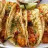 Mini baked chicken tacos topped with fresh ingredients and served on a plate.