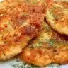 Crispy air fryer chicken cutlets on a plate served with dipping sauce.