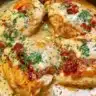 Creamy mustard chicken dish garnished with herbs on a white plate.